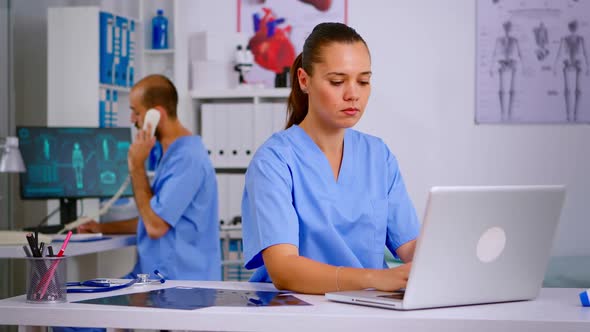 Medical Practitioner Typing Patient Health Report on Laptop