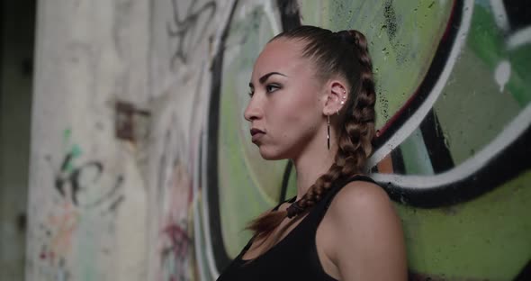 Passionate Look at Camera of a Brutal Girl Posing at Wall in Abandoned Building