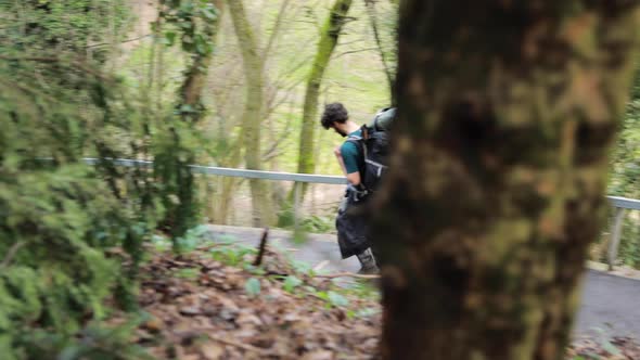 Backpacker guy trekking alone on hiking path outdoors. Slow motion