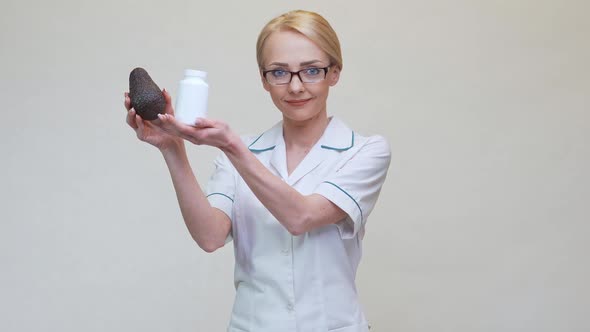 Nutritionist Doctor Holding Organic Avocado Fruit and Jar of Medicine or Vitamin or Omega 3 Capsules