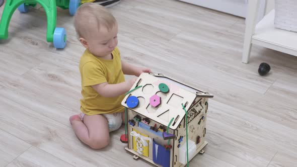 Baby Boy Playing with Wooden Busy House Montessori Educational Toy at Home