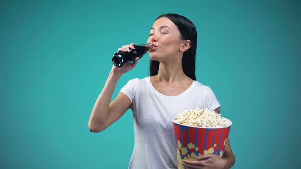 Asian Woman Holding Big Paper Cup With Popcorn and Drinking Soda Visiting Cinema