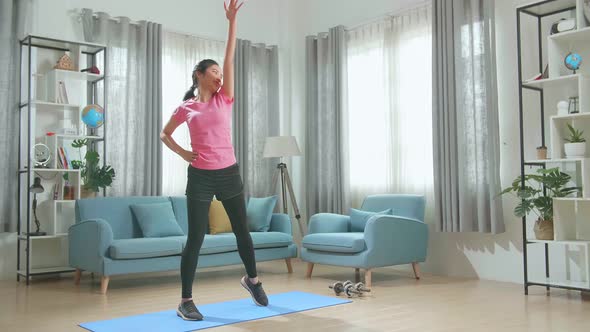 Asian Fit Beautiful Girl In A Pink Athletic Outfit Is Energetically Exercising In Her Living Room
