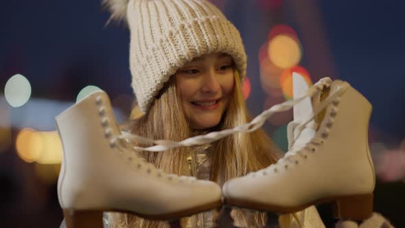 Closeup of Smiling Girl Admiring New Ice Skates with New Year Lights at Background