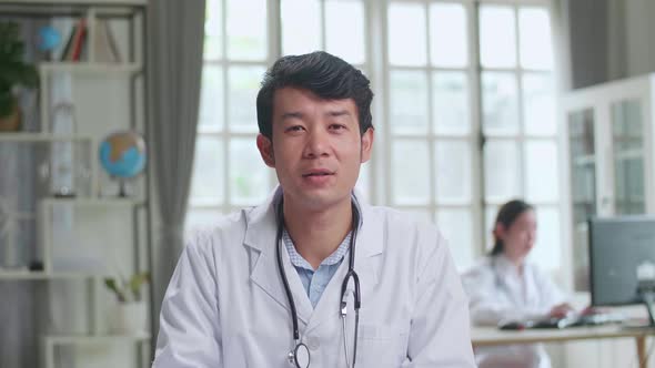 Asian Male Doctor Physician In White Medical Uniform Speaking Looking At Camera Make Video call