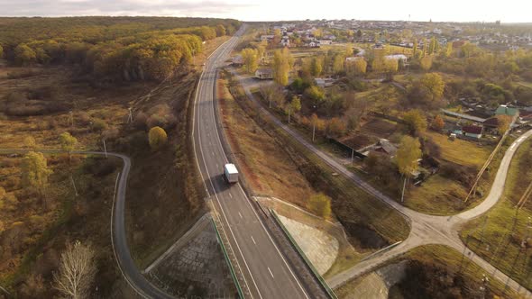 White Truck with Cargo Semi Trailer Moving on Autumn Road in Direction.