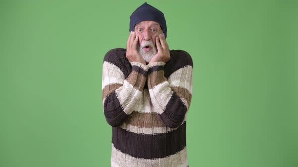 Handsome Senior Bearded Man Wearing Warm Clothing Against Green Background