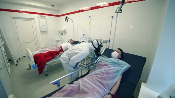 Doctor in a Hazmat Suit Is Examining a Patient in a Hospital