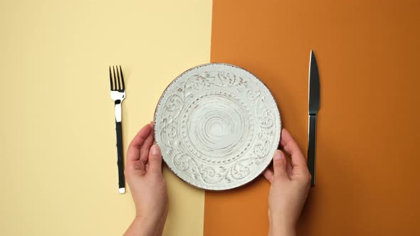 white round plate, knife with fork on brown background