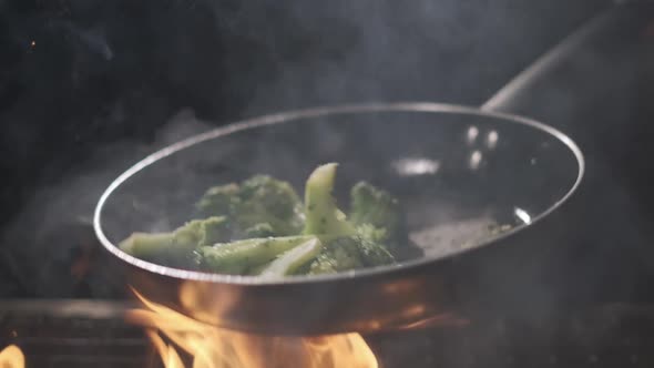 Cook Fries Broccoli in a Pan. Flying Vegetables. Cooking on Fire and Coal. Slow Motion