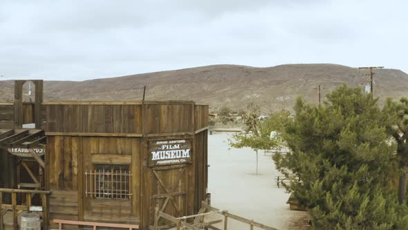 Aerial video flying up and over a western videoie set in the middle of a dry sandy desert in the mou