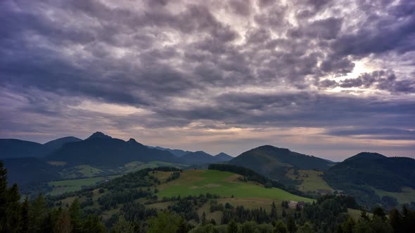 High clouds over a rural mountain landscape in spring. Dusk, transition from day to night.