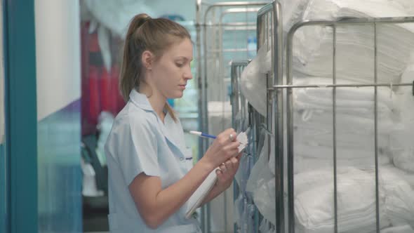 Woman taking inventory of towels in hotel laundry room