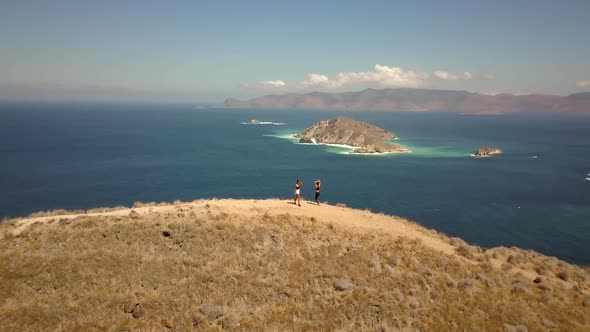 Two Happy Tourists Stand on the Top of the Hill Looking Over the Bay Admire the Wild Beauty of