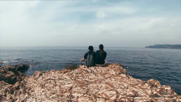 Couple in Love Sitting on a Rocky Edge By the Sea, Talking on Different Topics and Enjoy the View