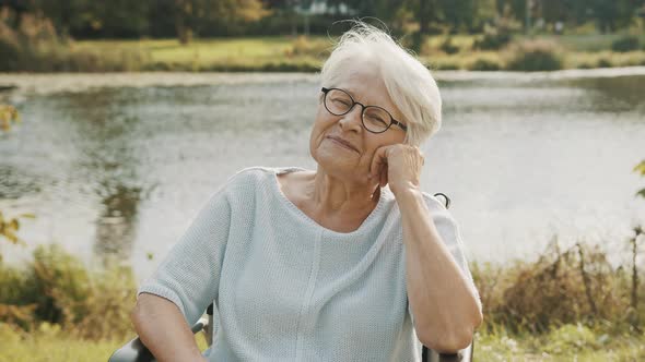 Pensive Old Woman in the Wheelchair Sitting Near the River 