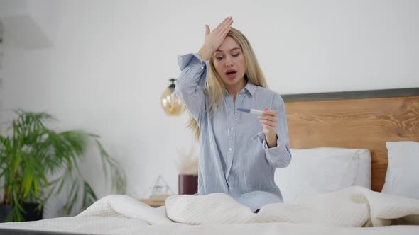 Shocked Caucasian Woman Holding Positive Pregnancy Test Making Facepalm Gesture