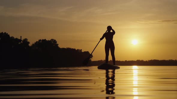 Woman Paddling on SUP Board at Sunset