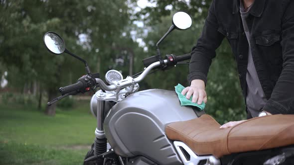 Wiping Leather Scrambler Motorbike with Cloth on the Street After Washing It