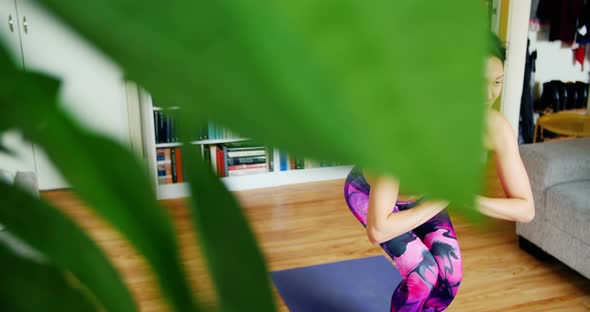 Beautiful woman practicing yoga in living room