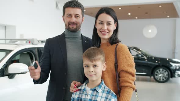 Portrait of Cheerful People Parents and Kid Standing Together in Automobile Showroom