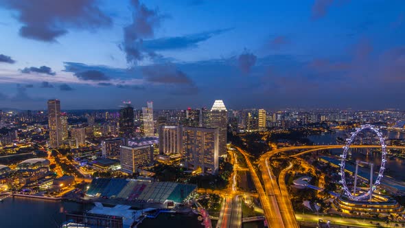 Skyline of Singapore with Famous Singapore Ferries Wheel Day To Night Timelapse at Twilight