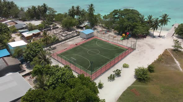 Drone flying over the beachand football field to the turquoise water of the ocean over the green tr