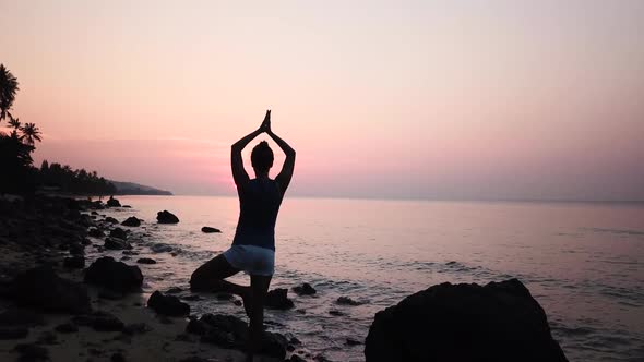 Silhouette of Standing Woman By Practicing Yoga on the Coast of Calm Sea on Sky Background