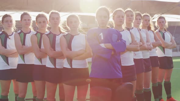 Female hockey players standing in a row with arms crossed