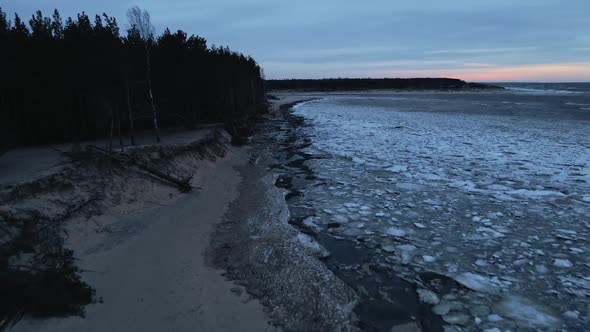 Scenic Sunset Ice Drifting with Fallen Trees During Windy Weather with Waves at Aerial View