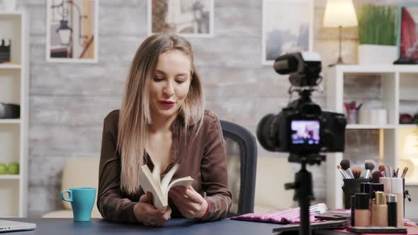 Attractive Beauty Blogger Reviewing a Book for Her Audience