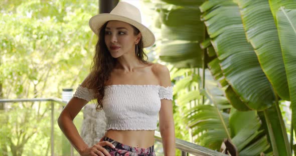 Confident Female Adjusting Hat on Balcony