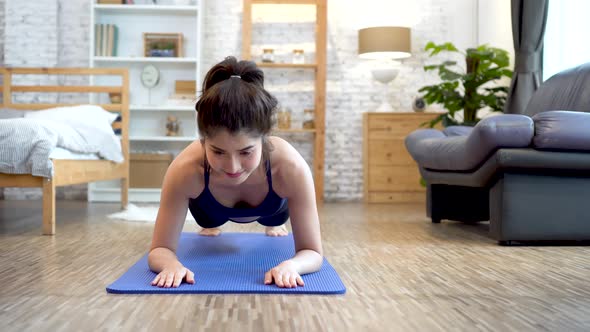 Fitness Asian Woman Exercising Plank at Home in Living Room with Cozy Sofa Home Interior Setting
