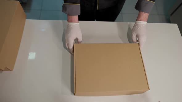 Top View of Male Hands in Gloves Passing Disposable Cardboard Box for Delivery Person in Restaurant