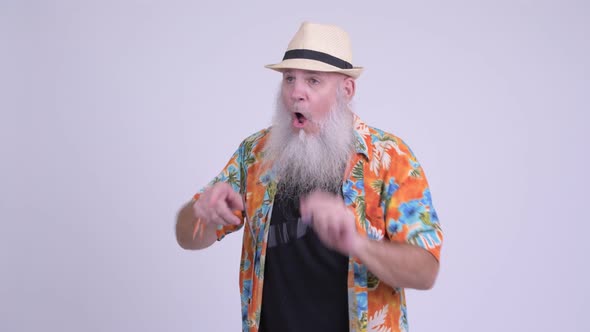 Happy Mature Bearded Tourist Man Looking Surprised While Pointing Finger