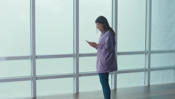 Stressed Woman Standing With Phone in Hands Looking at Phone Screen