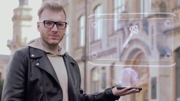 Smart Young Man with Glasses Shows a Conceptual Hologram Key