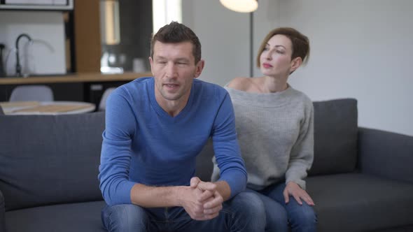 Irritated Unloving Husband Turning From Wife Touching Shoulder of Spouse