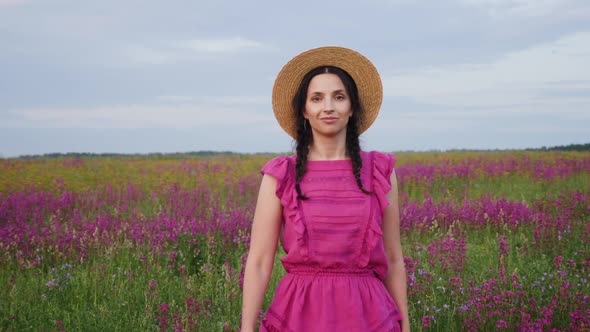 Girl in a Straw Hat and a Short Dress Walks on a Field