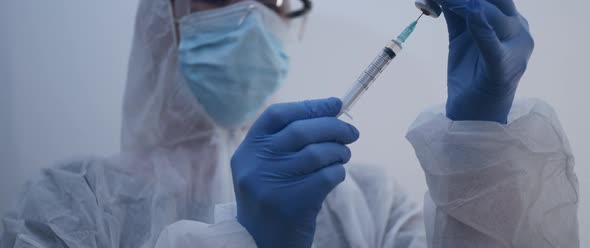 Person filling up syringe inserted to a bottle slow motion