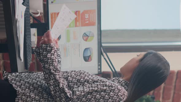 Vertical Video Close Up of Woman Comparing Data on Papers