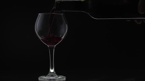 Rose Wine. Red Wine Pour in Wine Glass Over Black Background. Slow Motion