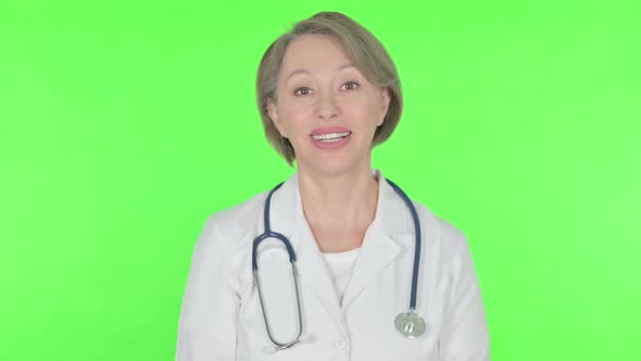 Old Female Doctor Talking on Online Video Call on Green Background