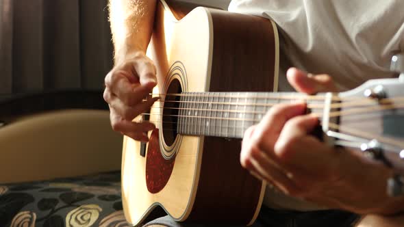 The Musician Plays a Fast Rhythm on a Yellow Acoustic Guitar. The Sun's Rays Pass Through the