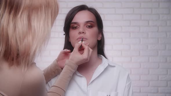 Makeup Artist Applying a Lip Pencil on a Model's Lips in the Studio