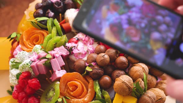 A beautiful decorated dessert bouquet of sweet dried fruits is filmed on a mobile phone camera. Deli