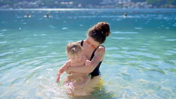 Asian Modern Mother Play Swim with Toddler Baby Boy in Tropical Sea