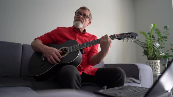 Senior Man Playing Acoustic Guitar at Home