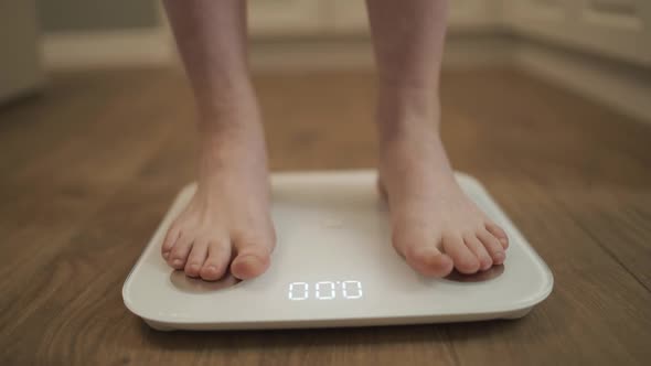 A Woman at Home Gets Her Feet on the Scales To Measure Her Weight
