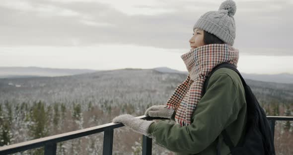 Happy Asian Lady Watching Wonderful Winter Landscape Looking at Forest and Mountains From Obsrvation